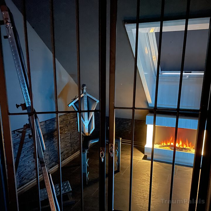 Blick ins Kaminzimmer mit weißem Kamin und Sessel.